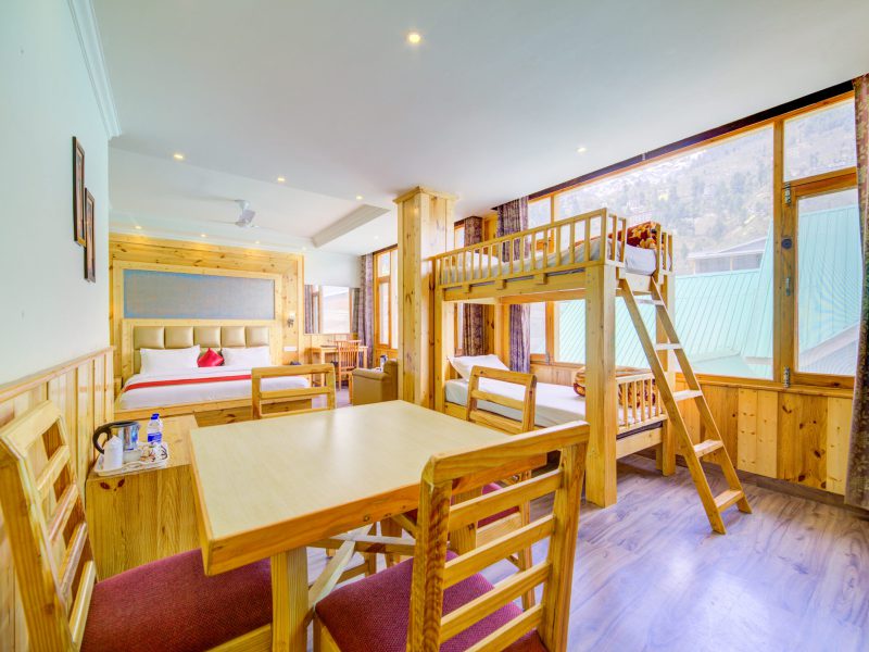 A Junior Family Suite at Grace Resort and Spa, Manali, with a dining area and wooden furniture.