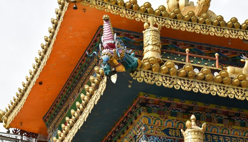 Close-up of the ornate golden decorations and vibrant artwork on the facade of a monastery in Dharamshala.