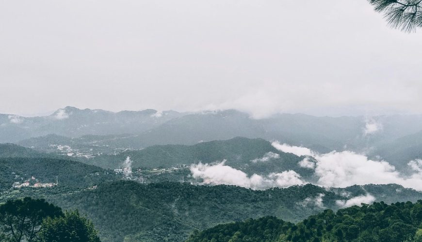 A misty view of Kasauli's lush green mountains with clouds rolling through the valleys.