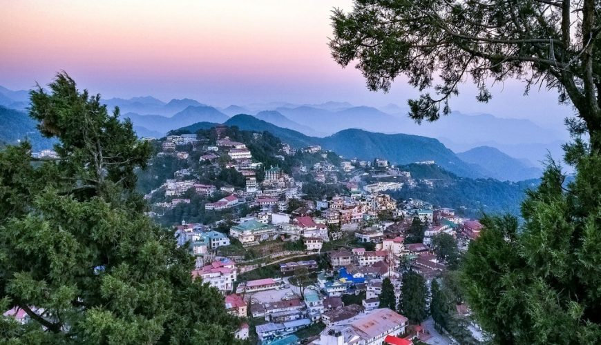 Aerial view of Mussoorie at dusk, showcasing the vibrant town against the serene backdrop of the Himalayan foothills.